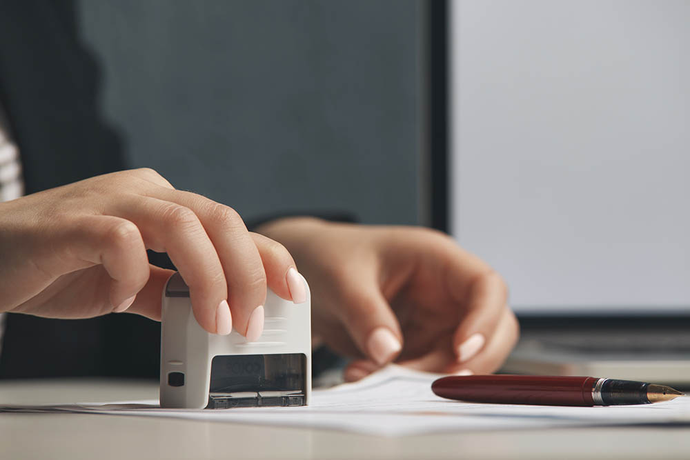 Close up on woman's notary public hand stamping the document. Notary public concept.