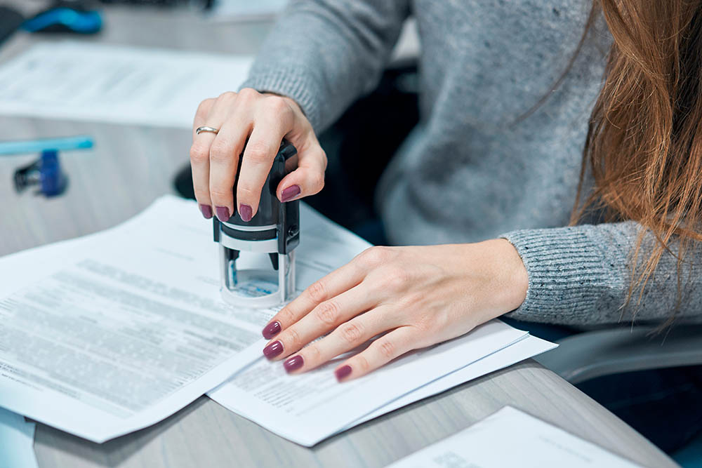 girl puts a stamp on documents in the office