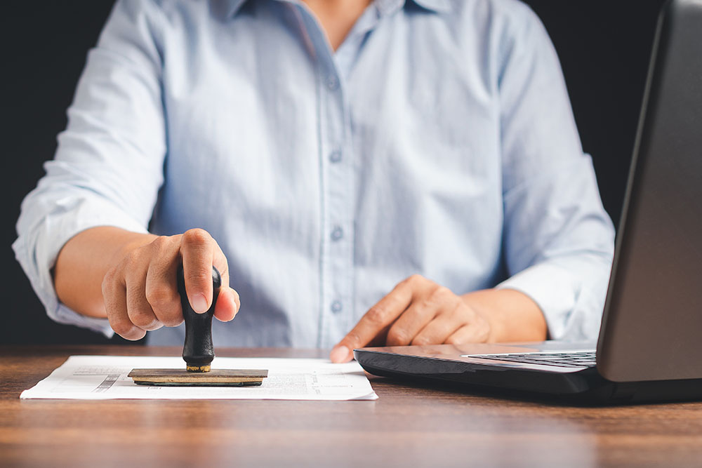 Businessman stamping approved on documents while sitting working in the office.
