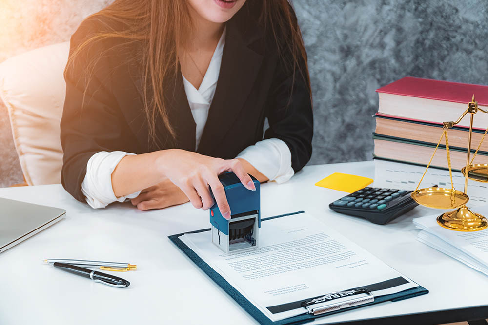 woman notary stamping document at table, close up.