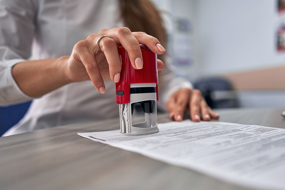 girl in the office puts a stamp on the documents
