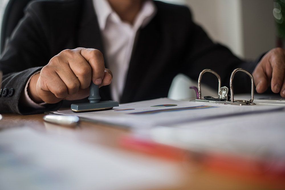 businessman hand pressing rubber stamp approved on business contract