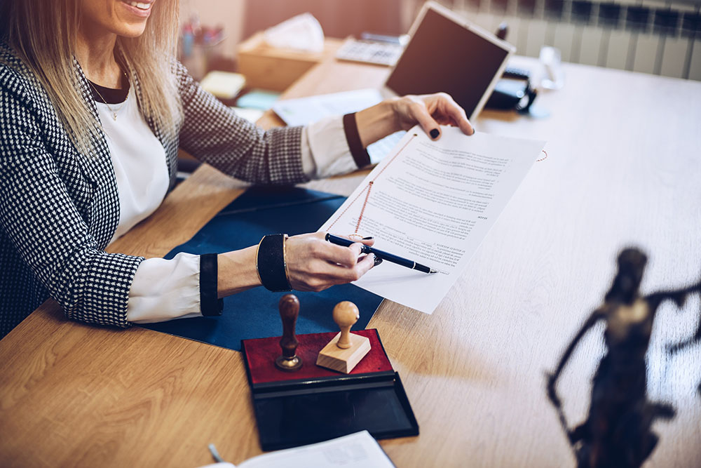 woman notary public holding pen and pointing at signature place.