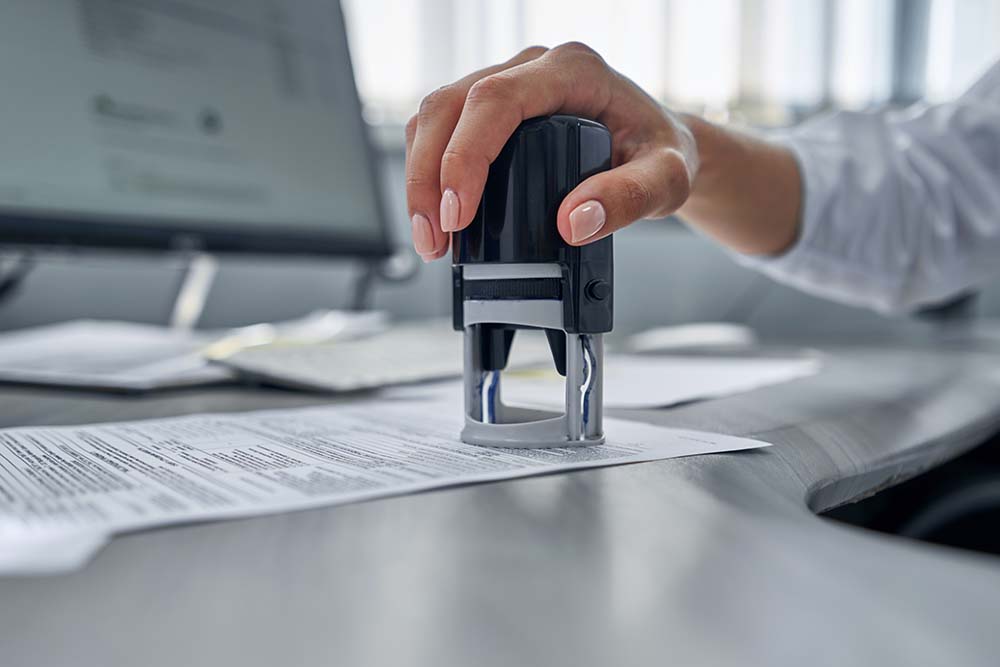 girl in the office puts a stamp on the documents