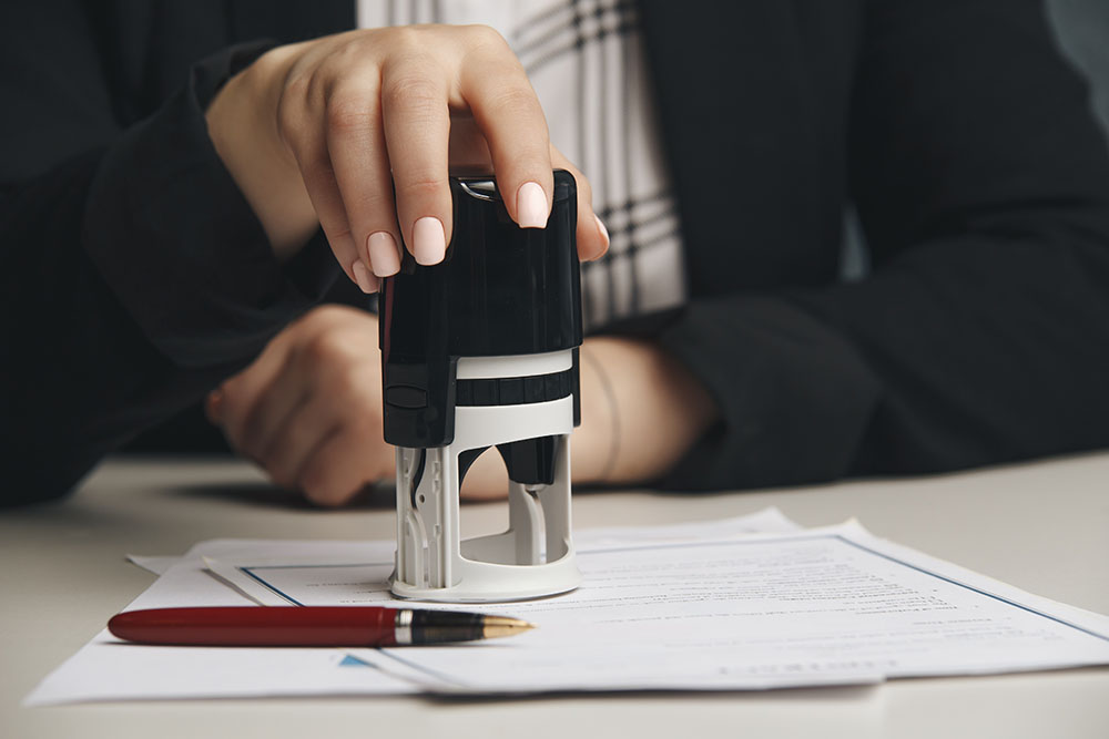 close up on woman's notary public hand stamping the document. notary public concept