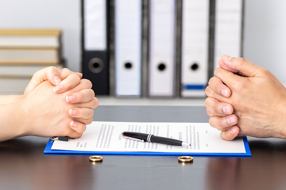 hands of wife and husband signing divorce documents
