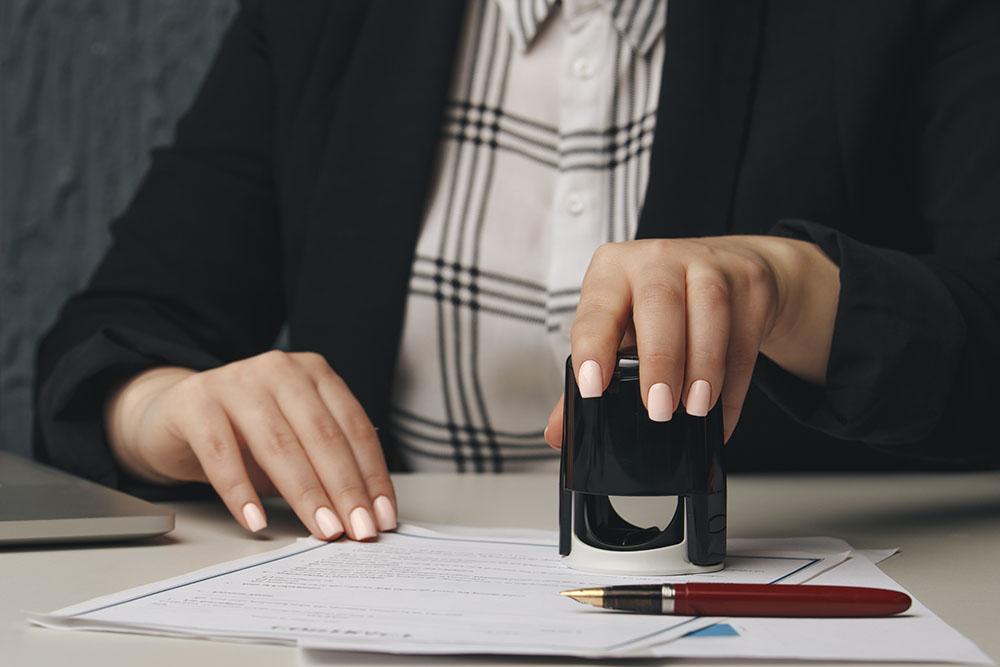 close up on woman's notary public hand stamping the document.