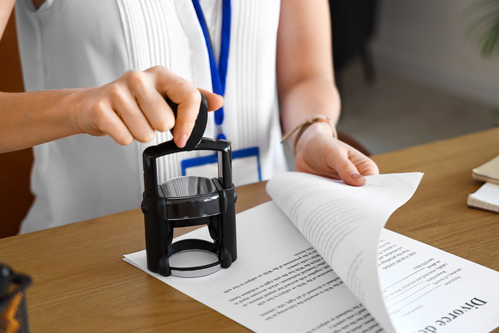 female notary public attaching seal to document in office