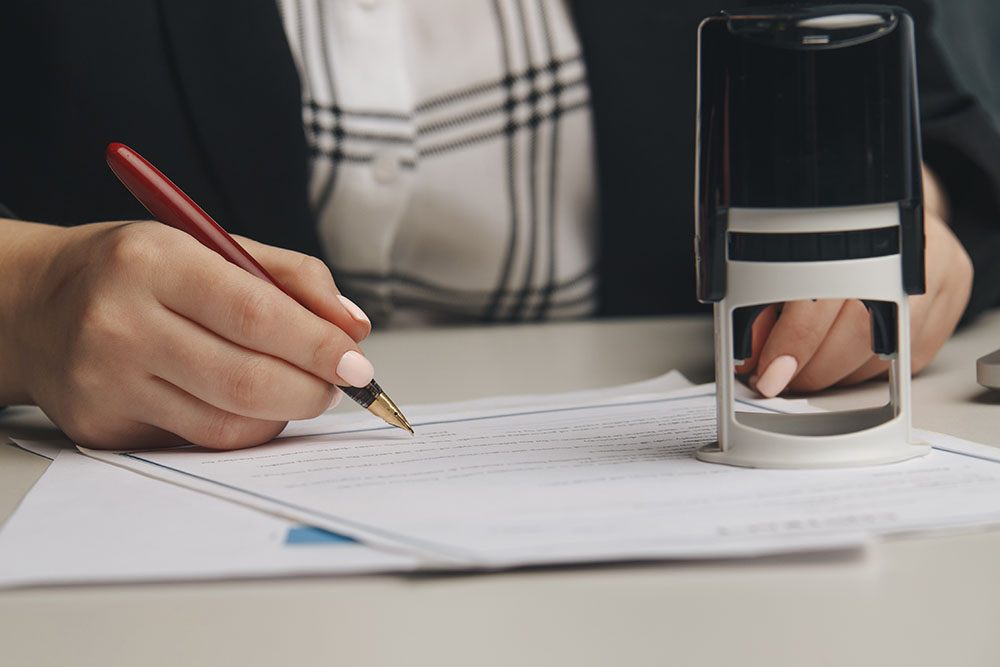 close up on woman's notary public hand stamping the document.