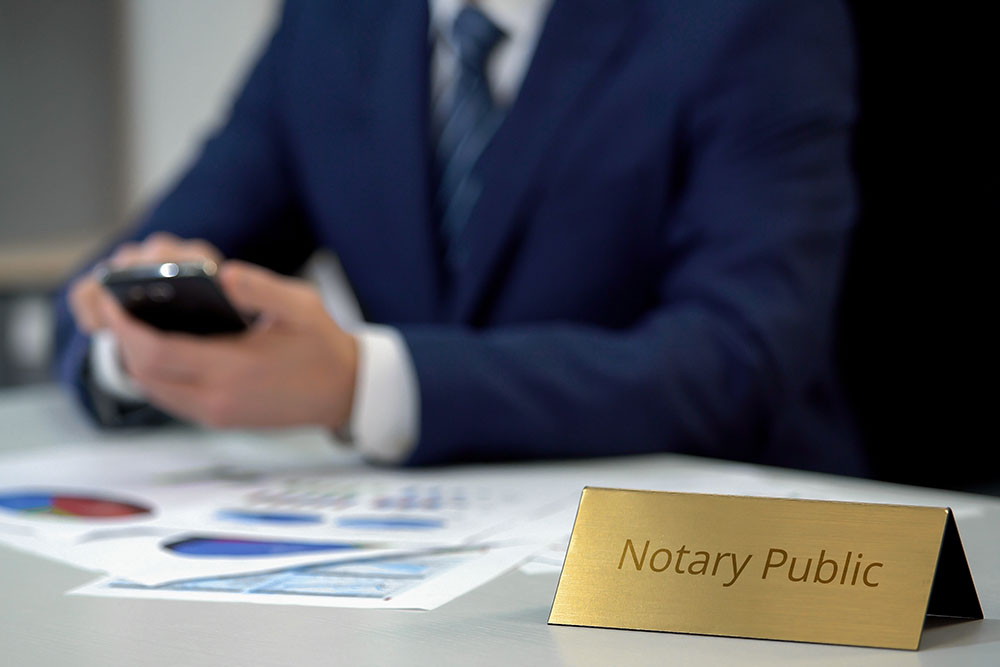 notary public holding smartphone and working with documents