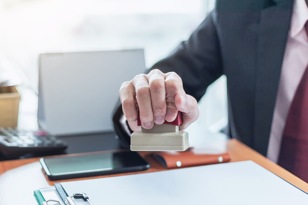 businessman stamping with approved stamp on document at office.