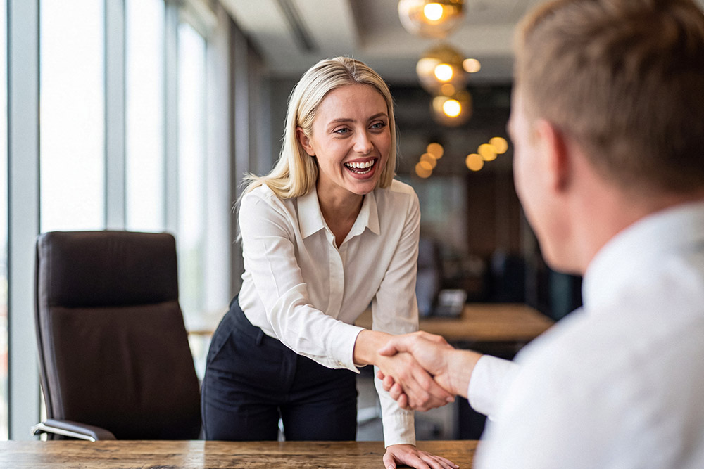 happy business woman shaking the hand of a new employee