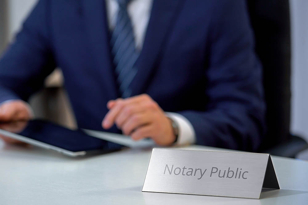 male notary public viewing files on tablet, checking documents