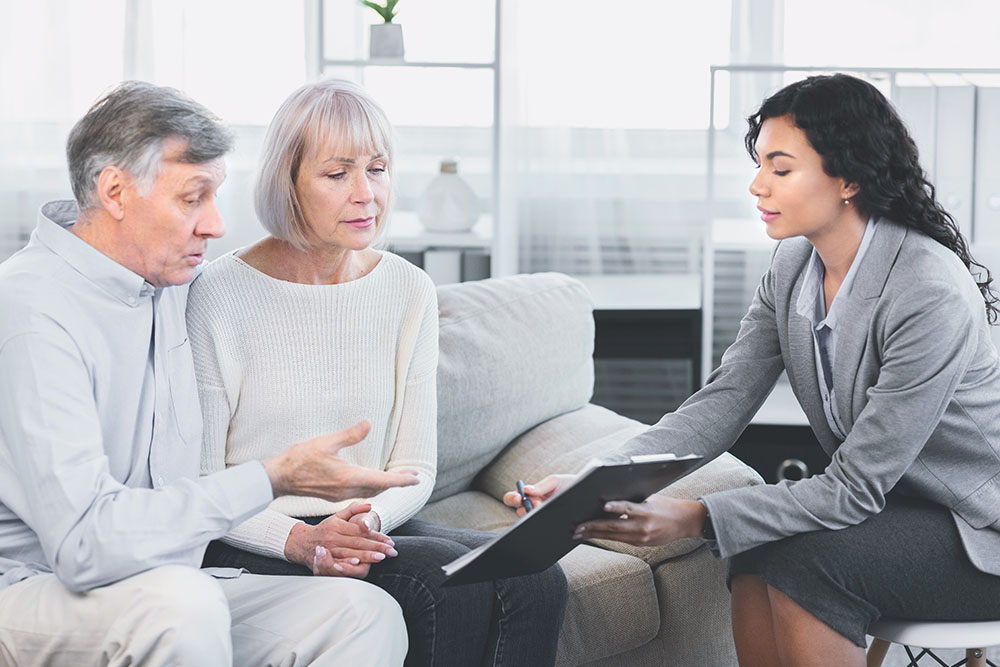 aged couple talking to their financial advisor and signing documents