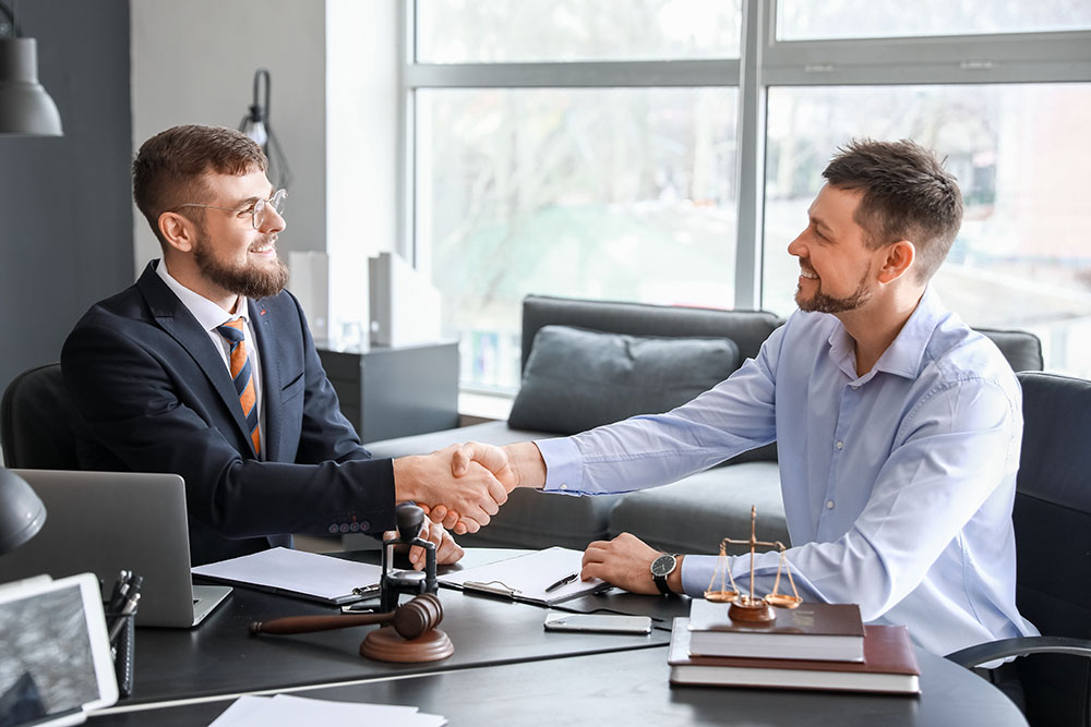 male lawyer with client shaking hands in office